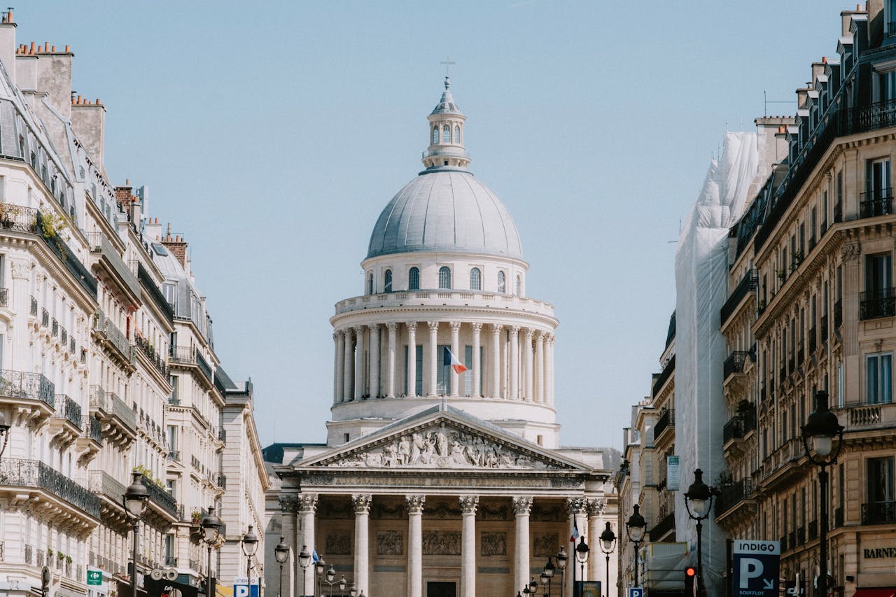 A captivating view of the Pantheon in Paris framed by classic architecture under a vibrant blue sky.