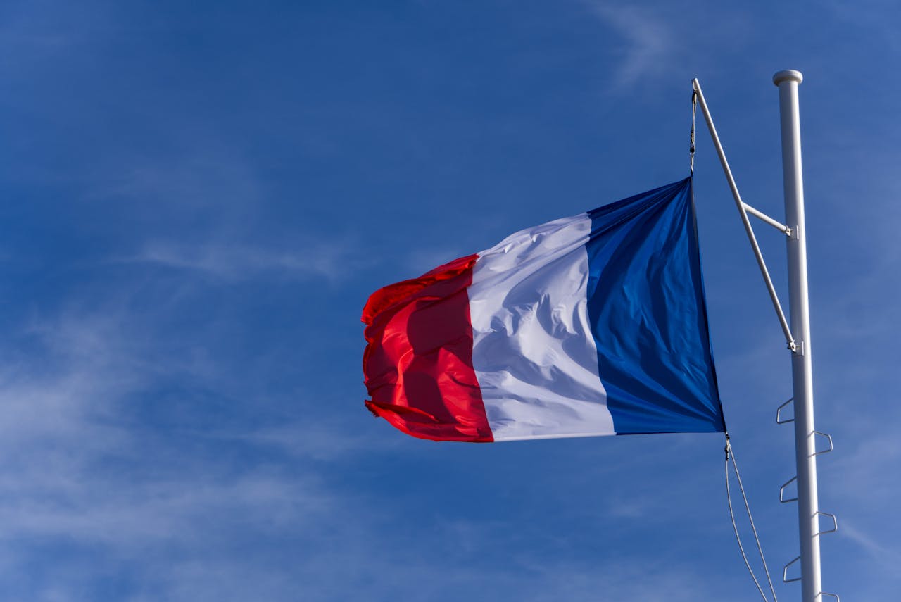 French national flag waving on flagpole under a bright clear blue sky in Le Pouliguen.