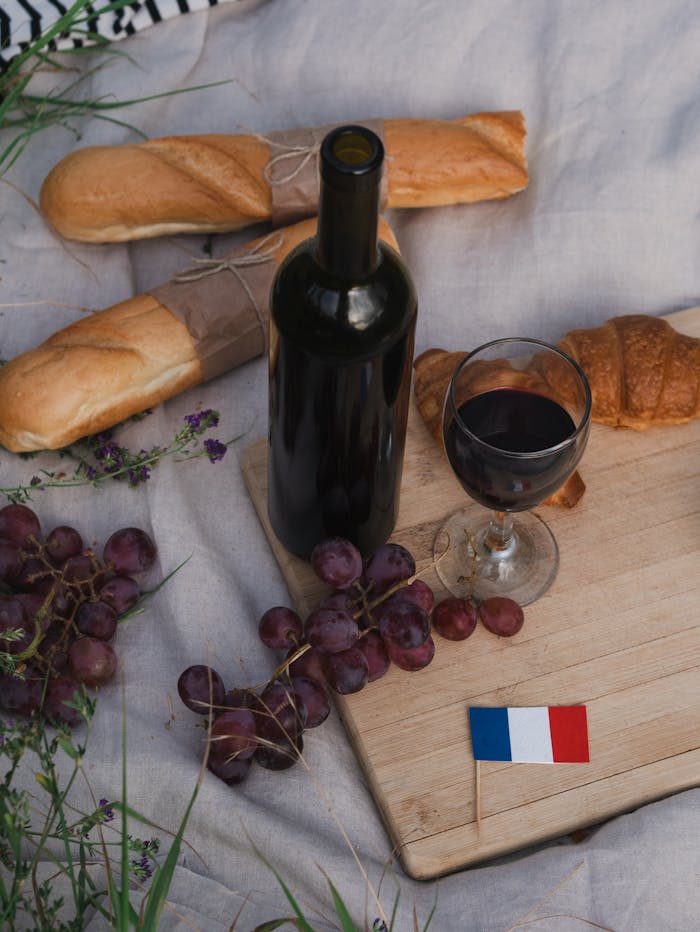 Elegant French picnic scene with wine, baguettes, and a French flag.